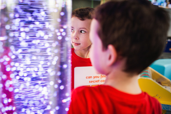 A young boy looking at a light display amused
