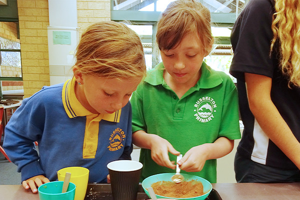 Two primary children making an experiment from brown powder.