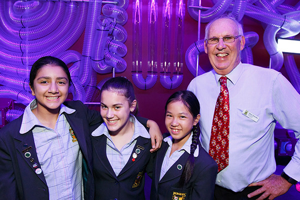 Three high school girls posing with a middle aged man at Scitech.