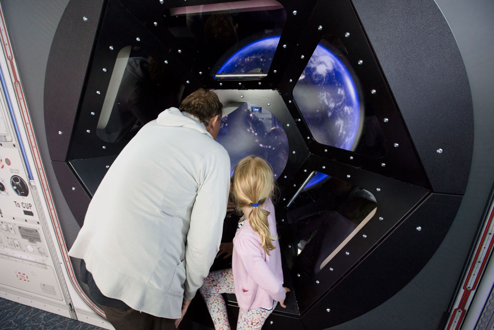 Parent and young girl looking into exhibit of the earth at Scitech.