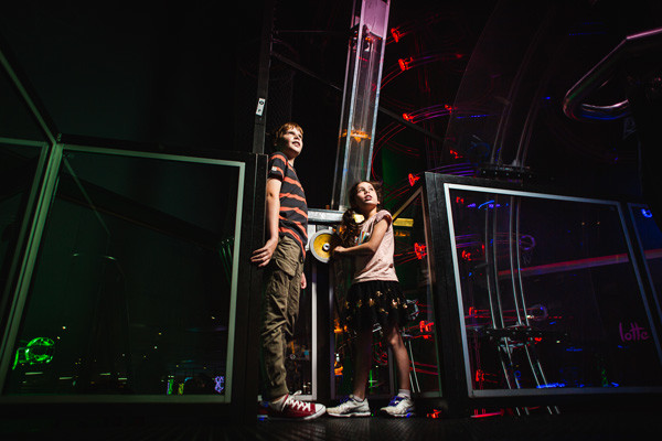 Two children looking up at coloured lights.