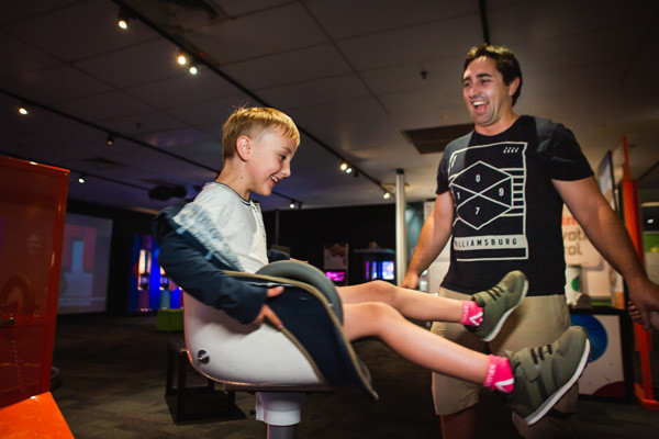 Young boy and adult man playing on spinning chair exhibit.