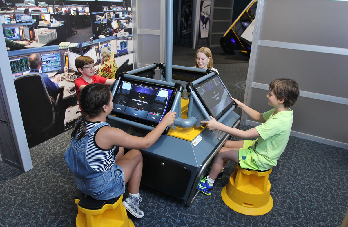 A group of four children each using a computer screen in a circle.