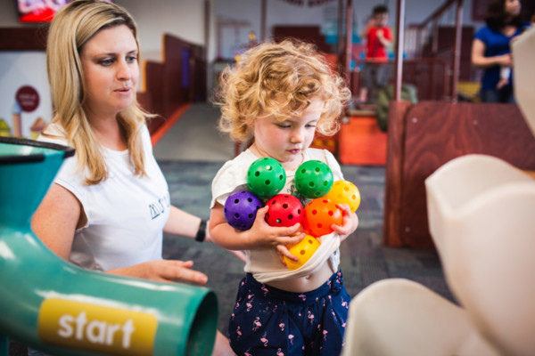 Young girl playing with coloured, plastic balls in Discoverland.