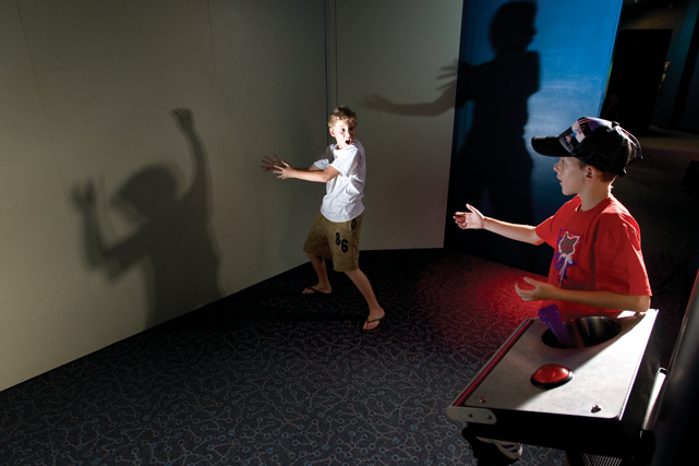 Two boys playing hand puppets and facing each other in a room.