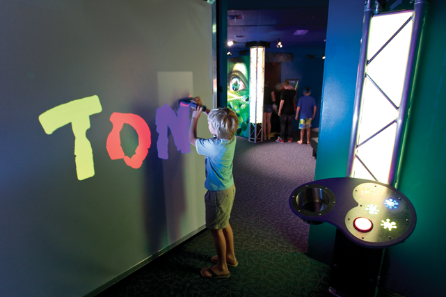 A young boy spelling out the letter T O N on a wall in colour.