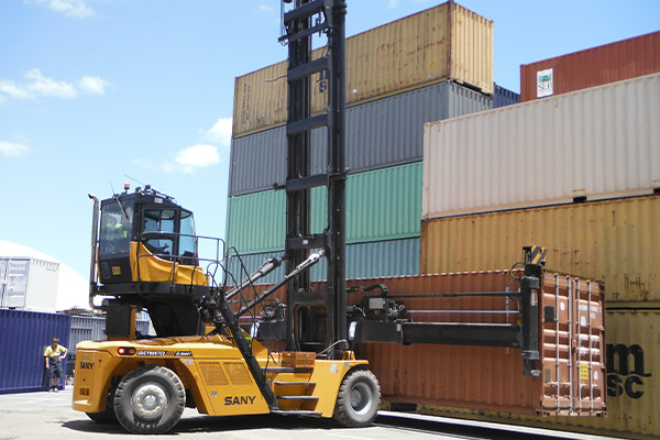 Forklift lifting shipping container in shipping container yard