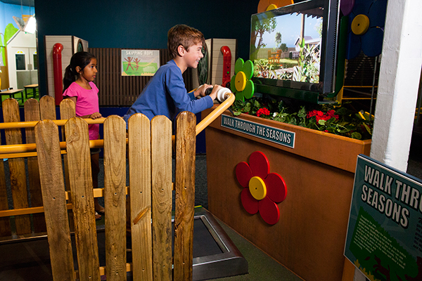 A young boy walking on a treadmill watching a seasons simulator on a screen.