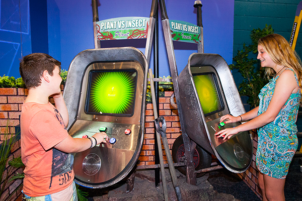 Two children playing on the Plants vs Insects computer simulator against each other.