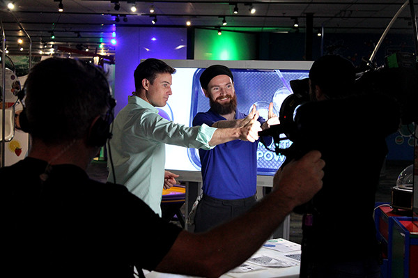 Behind the camera shot of two men giving thumbs up to camera