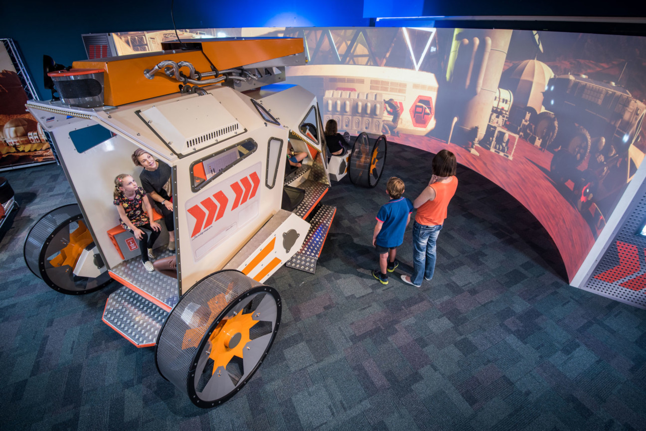 Some children playing in a simulation and large scale model of a mars rover in the Scitech Exhibition Space.