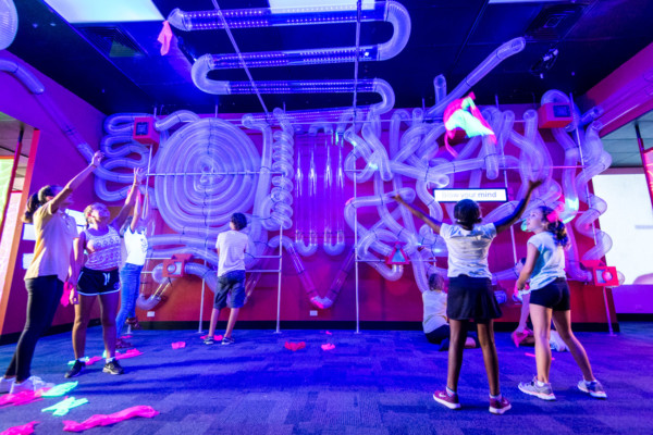 A group of children playing in a UV lit up space, the Kaartdjin Koorliny Gallery.