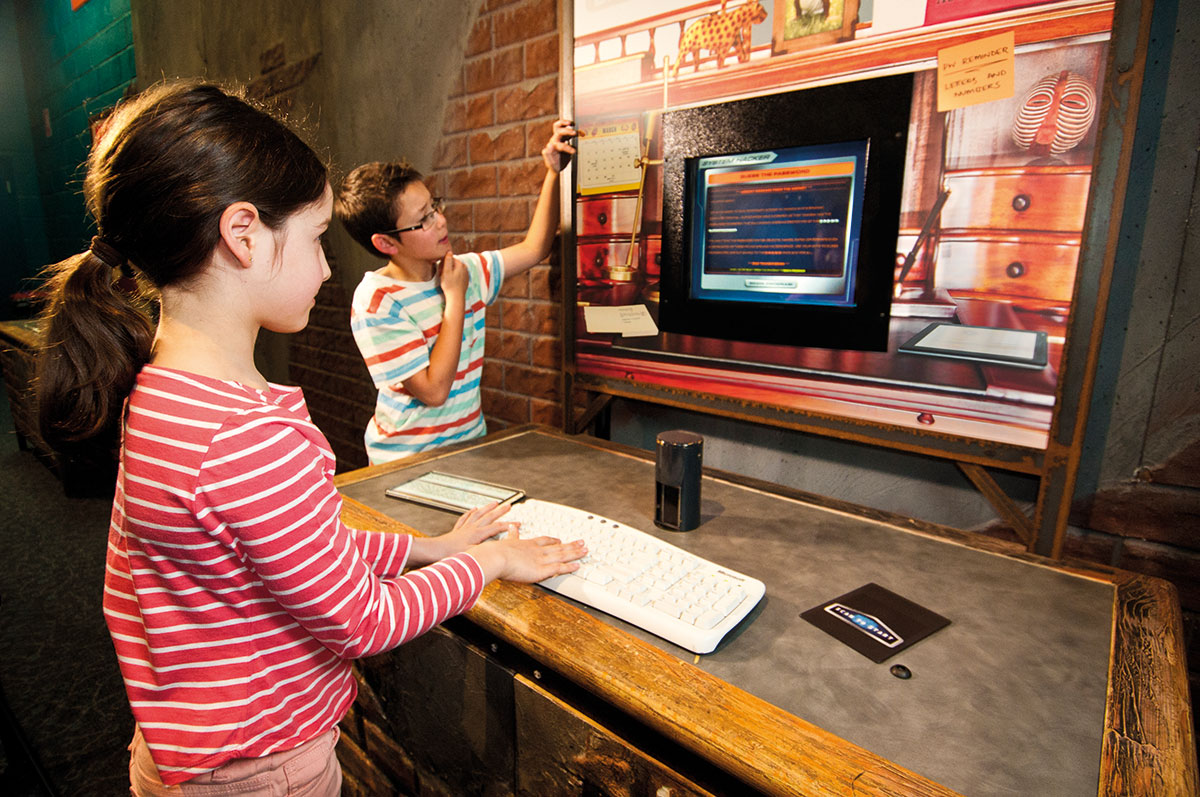 A young girl typing on a white keyboard looking at a computer monitor.