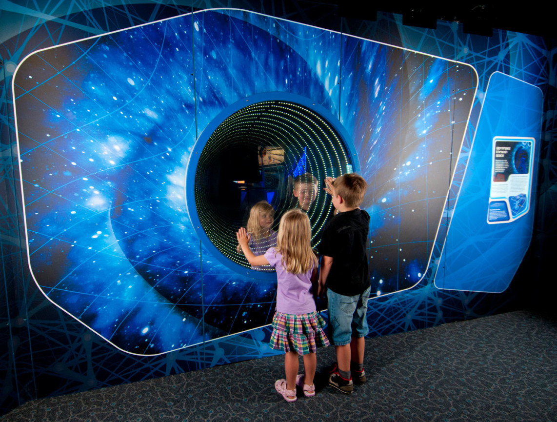 Two young children playing infront of a worm hole simulator in the Science Fiction Science Future Exhibition.