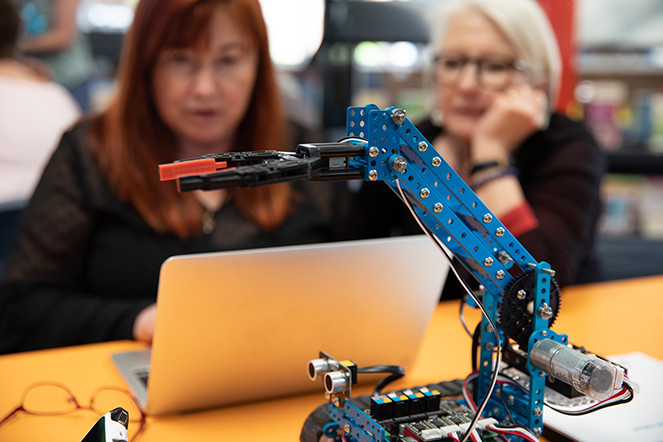 woman looking at laptop and robotic arm