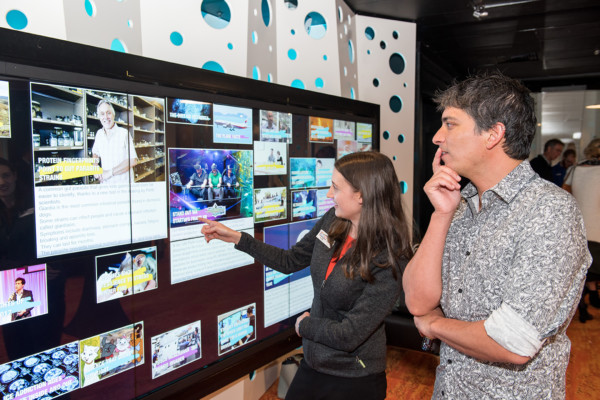 Two adults looking at a science information wall at Scitech Alumni event