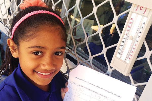 Young girl taking temperature readings and showing the recordings on paper.