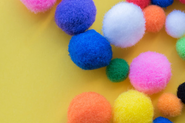 Colourful fabric pom poms on a table.
