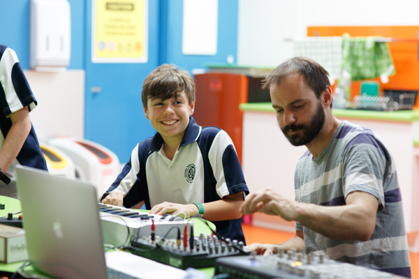 An adult and teenage boy playing with sound mixing equipment