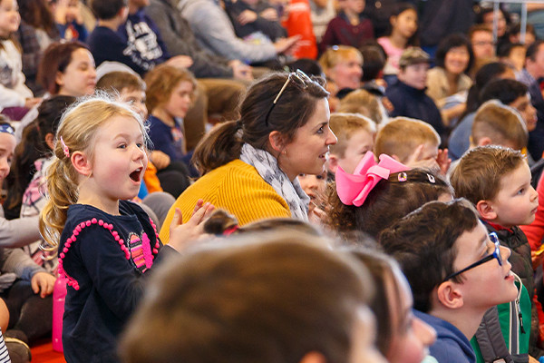 A large crowd of small children cheering at the stage.