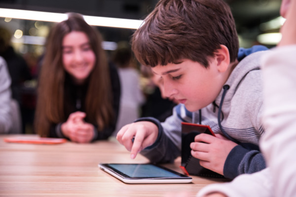 A young boy using an iPad on a desk.