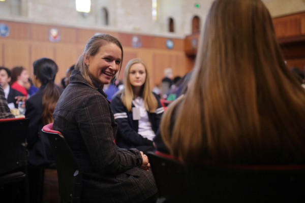 An adult woman having a happy conversation with two high school girls.