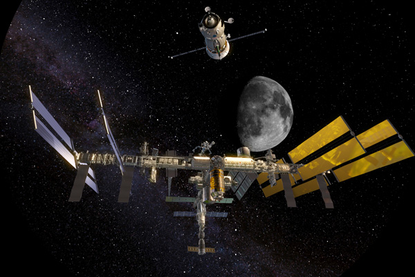 Photo of the International Space Station flying through the starry sky, with the moon in the background.