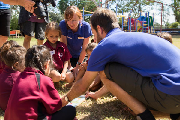 Science presenters show students an activity on the grass.
