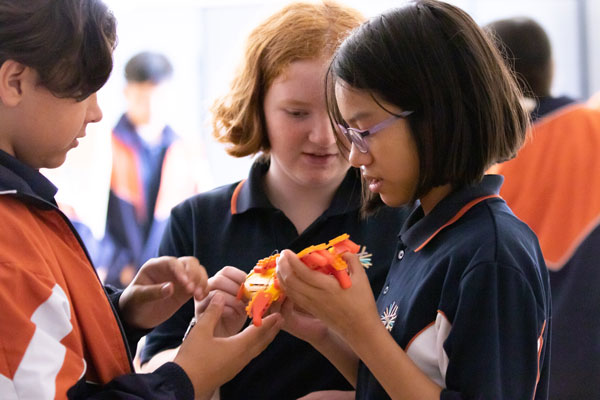 Students standing close together, holding a 3D printed creation.