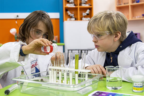 Two students pouring liquids into test tubes.