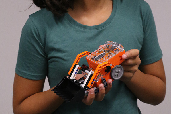 Close up of a person holding a small robotic digger.