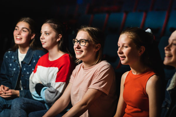 A group of girls watching a show, smiling and laughing.