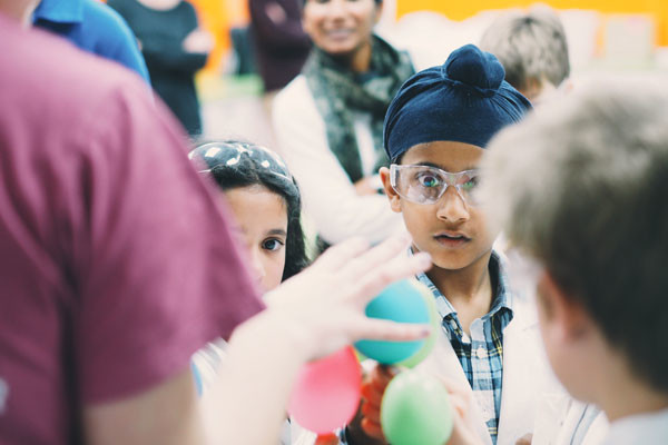 Young scientists looking excitedly at balloons.
