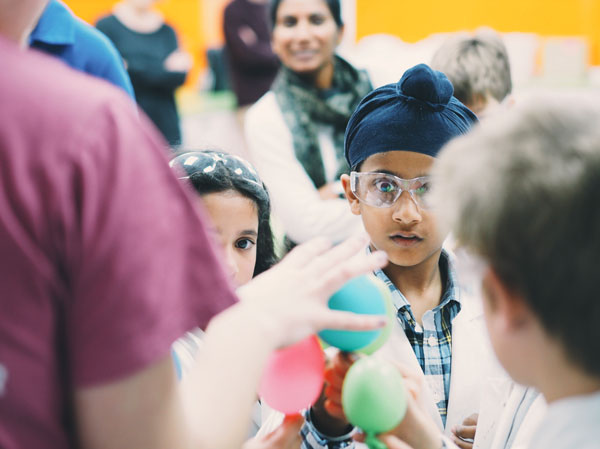 Young scientists looking excitedly at balloons.