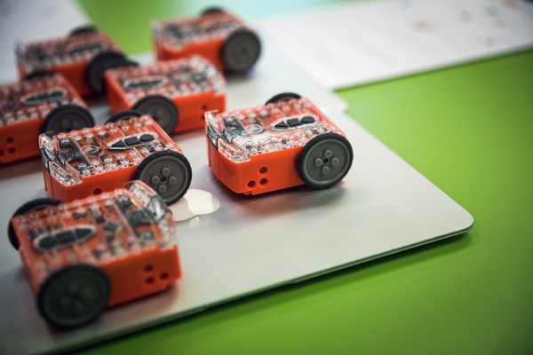 Close up of several small robotics devices, sitting on a laptop.