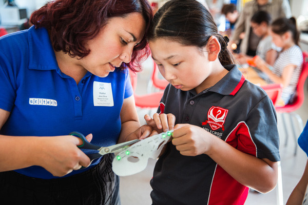 Science presenter and student cutting out a mask with LED lights.