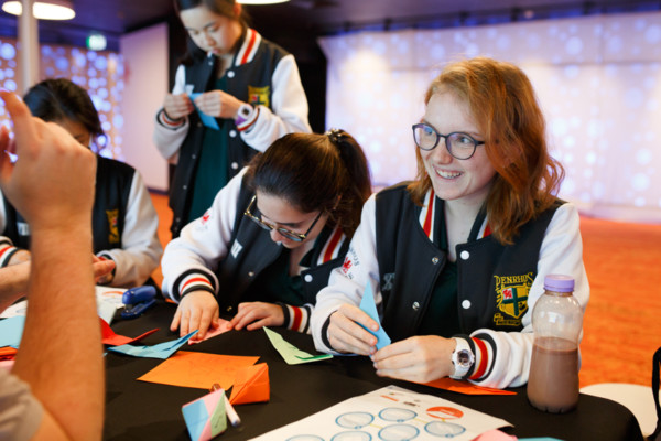 A group of high school students making origami objects.