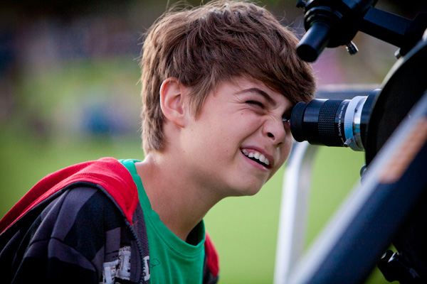 Young boy looks into telescope viewfinder.