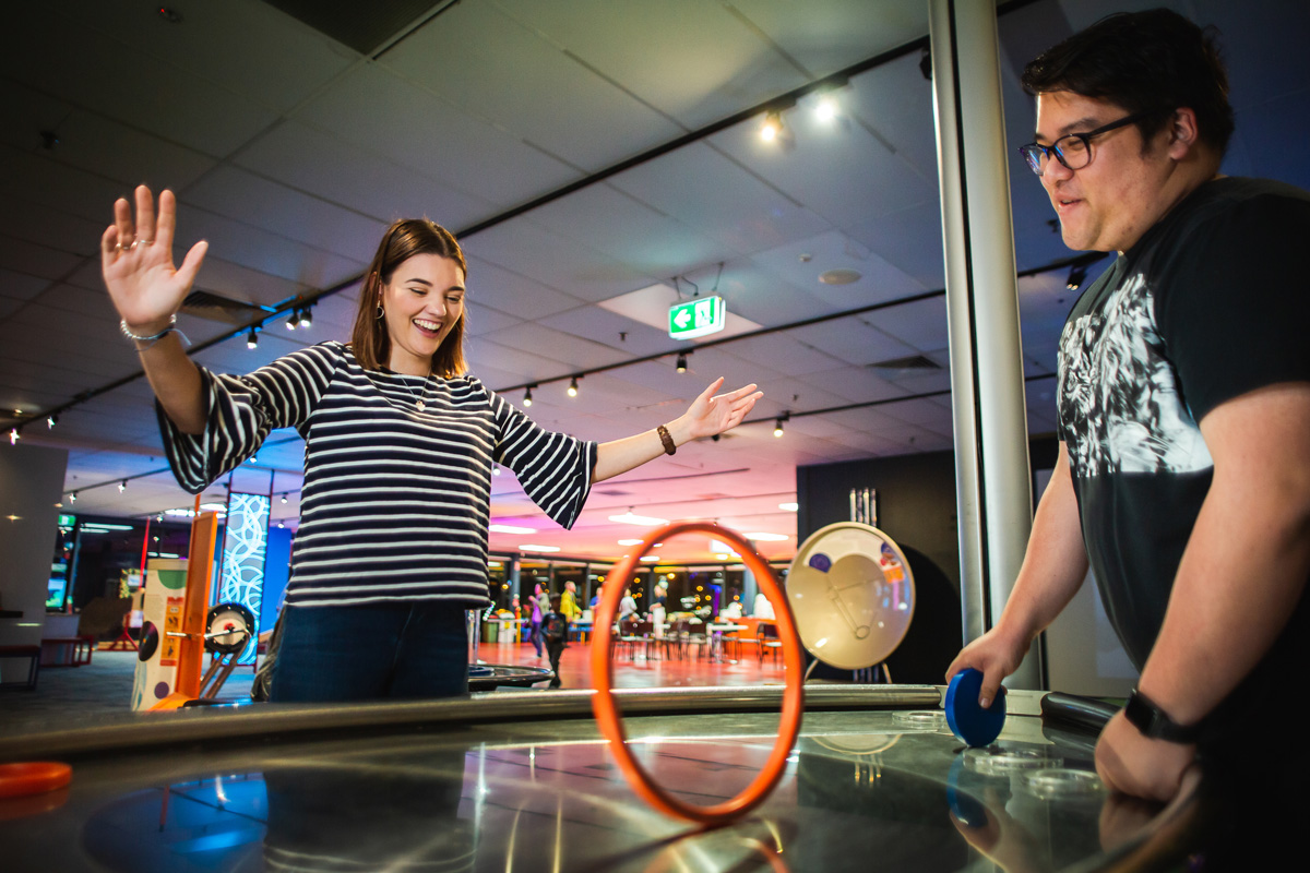 Two young adults play with a gravity exhibit