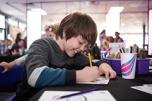 Young boy colours in at a table.