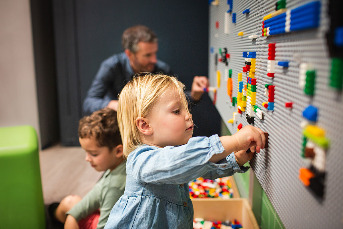 A young blond toddler playing with a peg wall