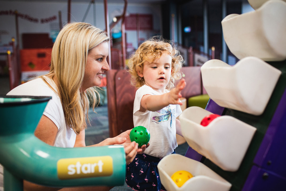Woman and toddler playing in Discoverland with coloured plastic balls
