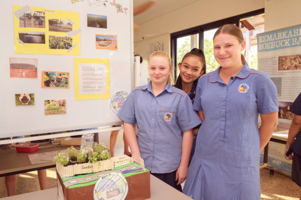 Students stand proudly with mini garden project in classroom