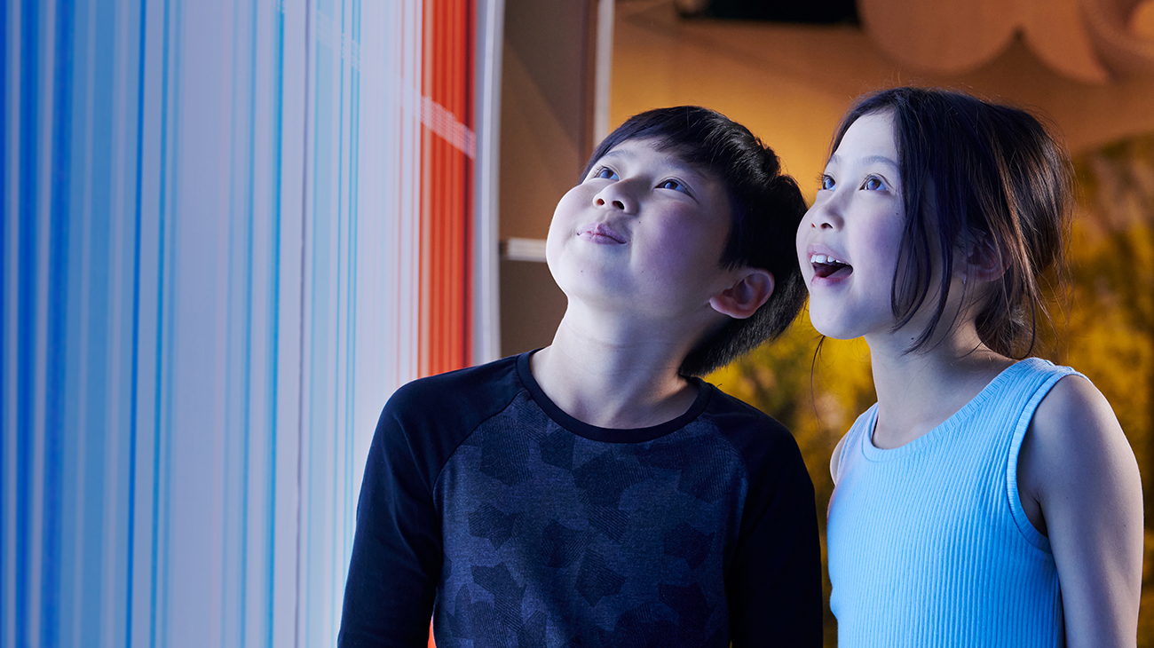 Boy and girl look up amazed at coloured wall