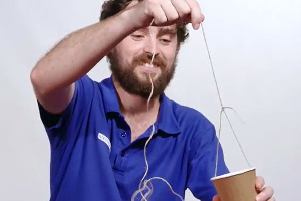 A man with a bright blue shirt with a cup with string around it.