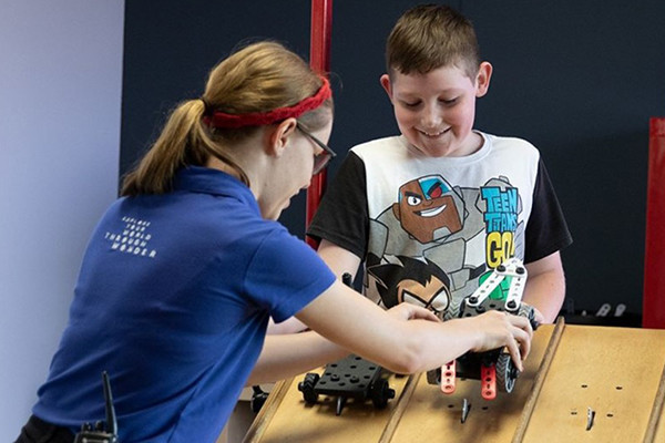 A young boy playing with a ramp and car toys.