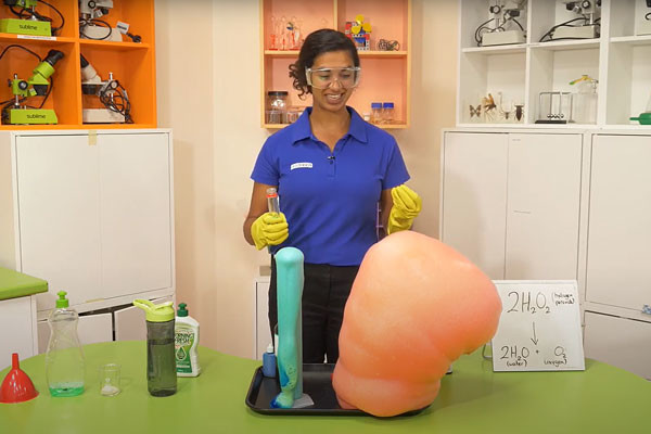 A scitech science presenter creating a reaction of coloured foam called elephants toothpaste.