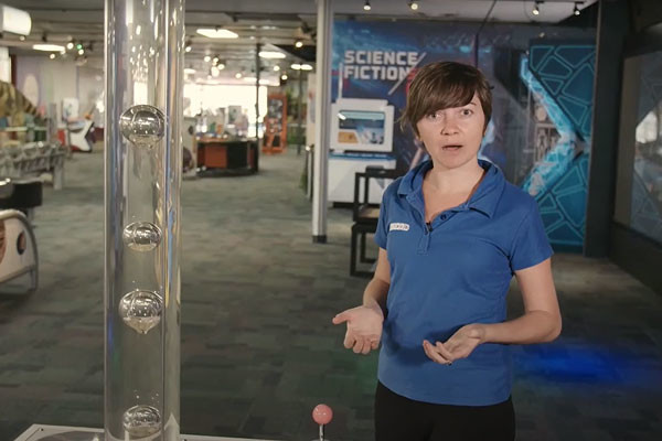 A woman in Scitech standing next to the bubble exhibit explaining the science behind bubbles.
