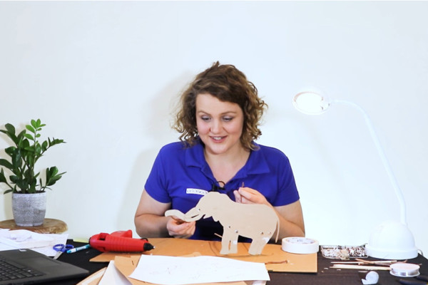 A woman holding an elephant cut out for shadow puppets activity