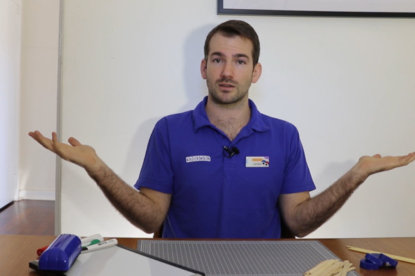 A man in a blue shirt talking to a camera with his hands gesticulating.